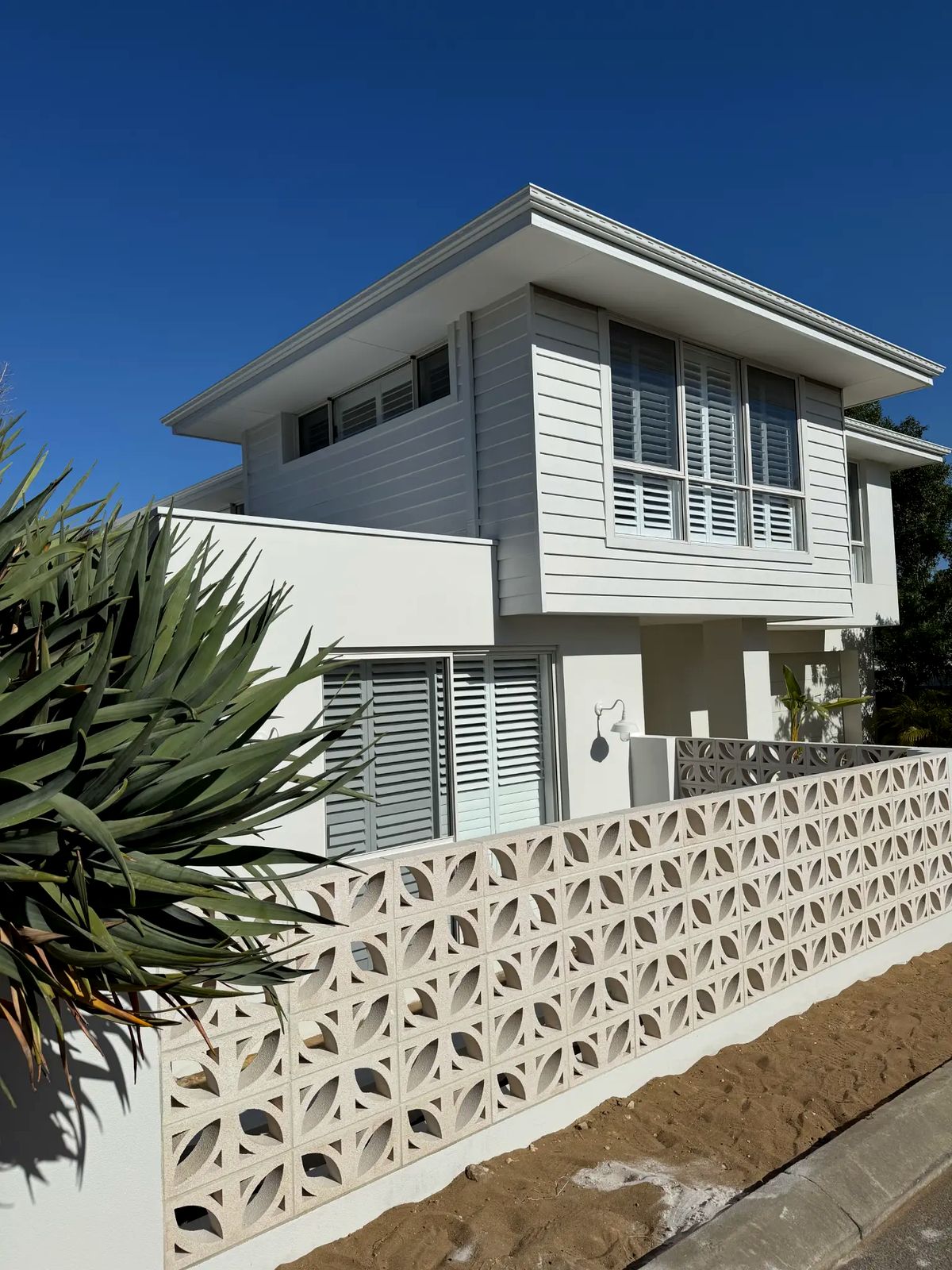 Perth custom built beach house with designer breeze block wall, white weatherboard cladding, and drought-resistant landscaping
